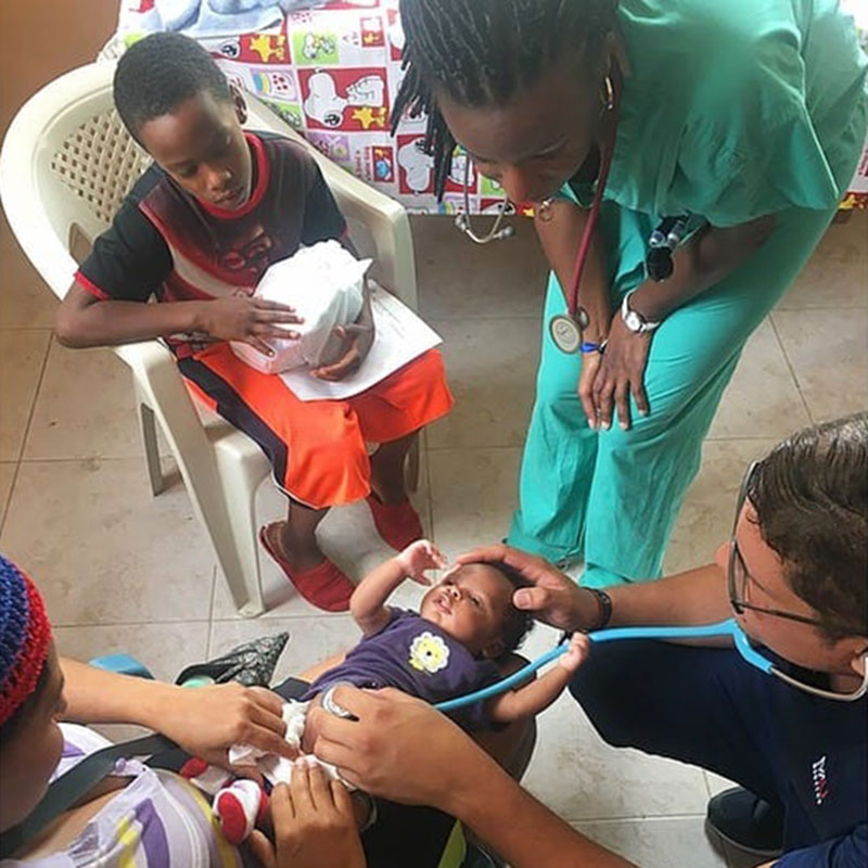 Dr. Angel Matos & UMHS student Natalie Cazeau treat a baby & his young mother at the UMHS medical mission in La Caleta, Boca Chica, Dominican Republic. Photo: UMHS Med4You