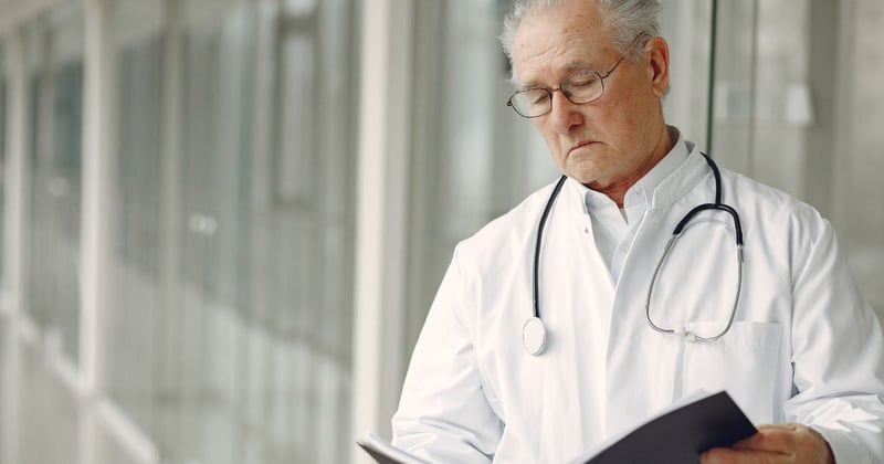 older doctor looking at chart