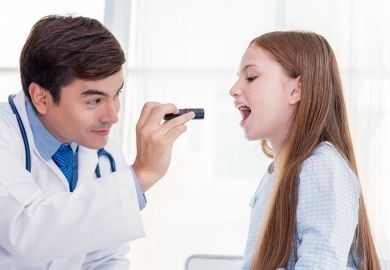 pediatric-specialist-examining-throat-of-girl-with-light
